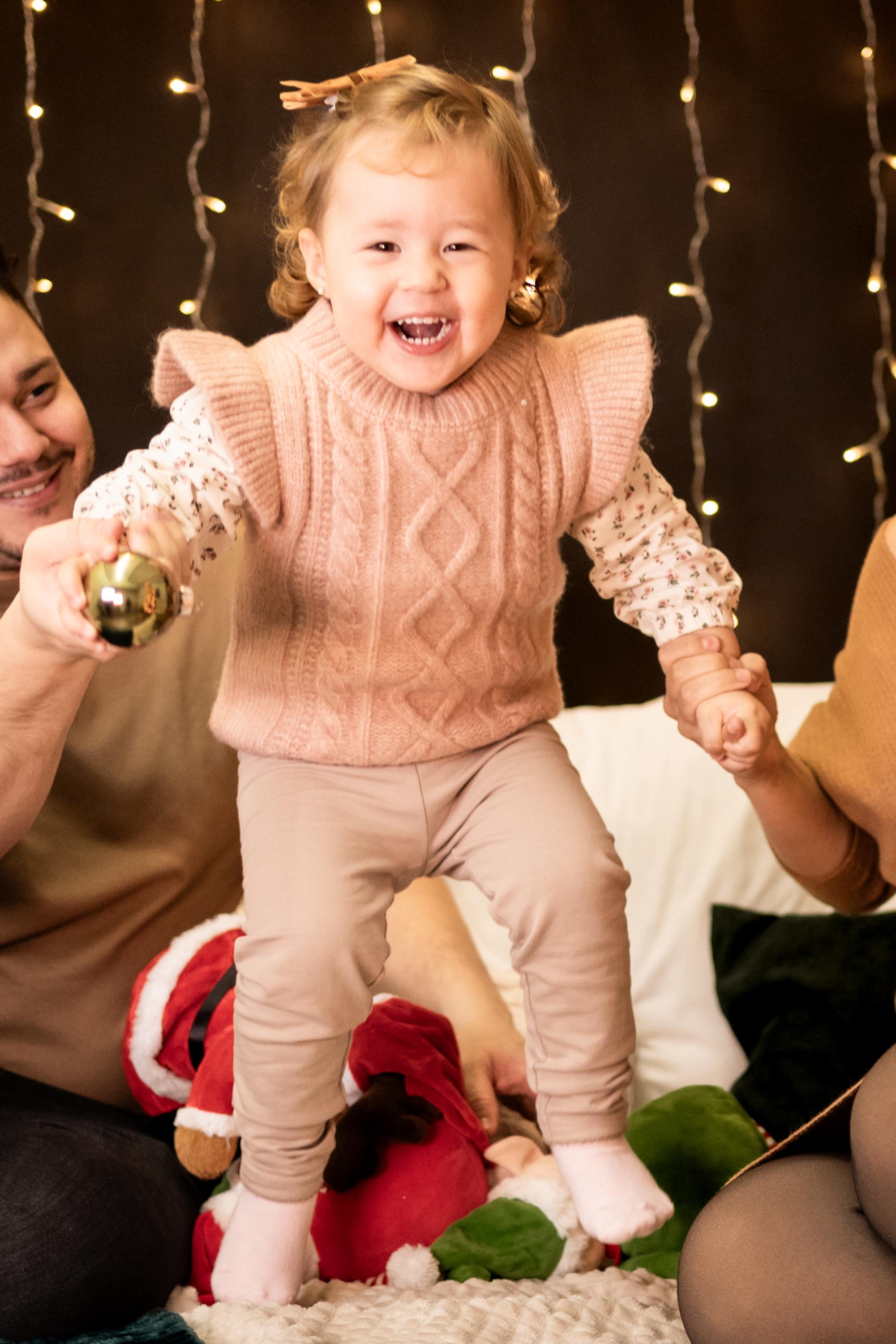 An adorable child stands near a Christmas tree, capturing the magic of the holiday season.