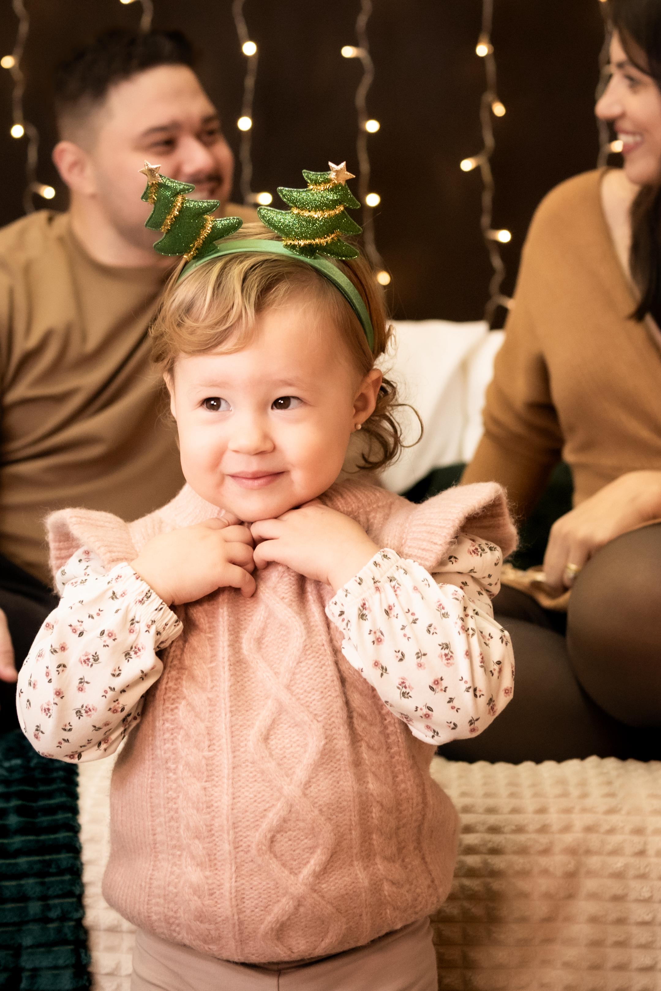 A joyful little girl runs towards her mother with excitement in front of a beautifully decorated Christmas tree.